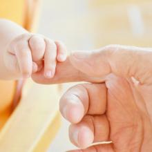 Mano de una persona adulta sosteniendo la mano de un niño